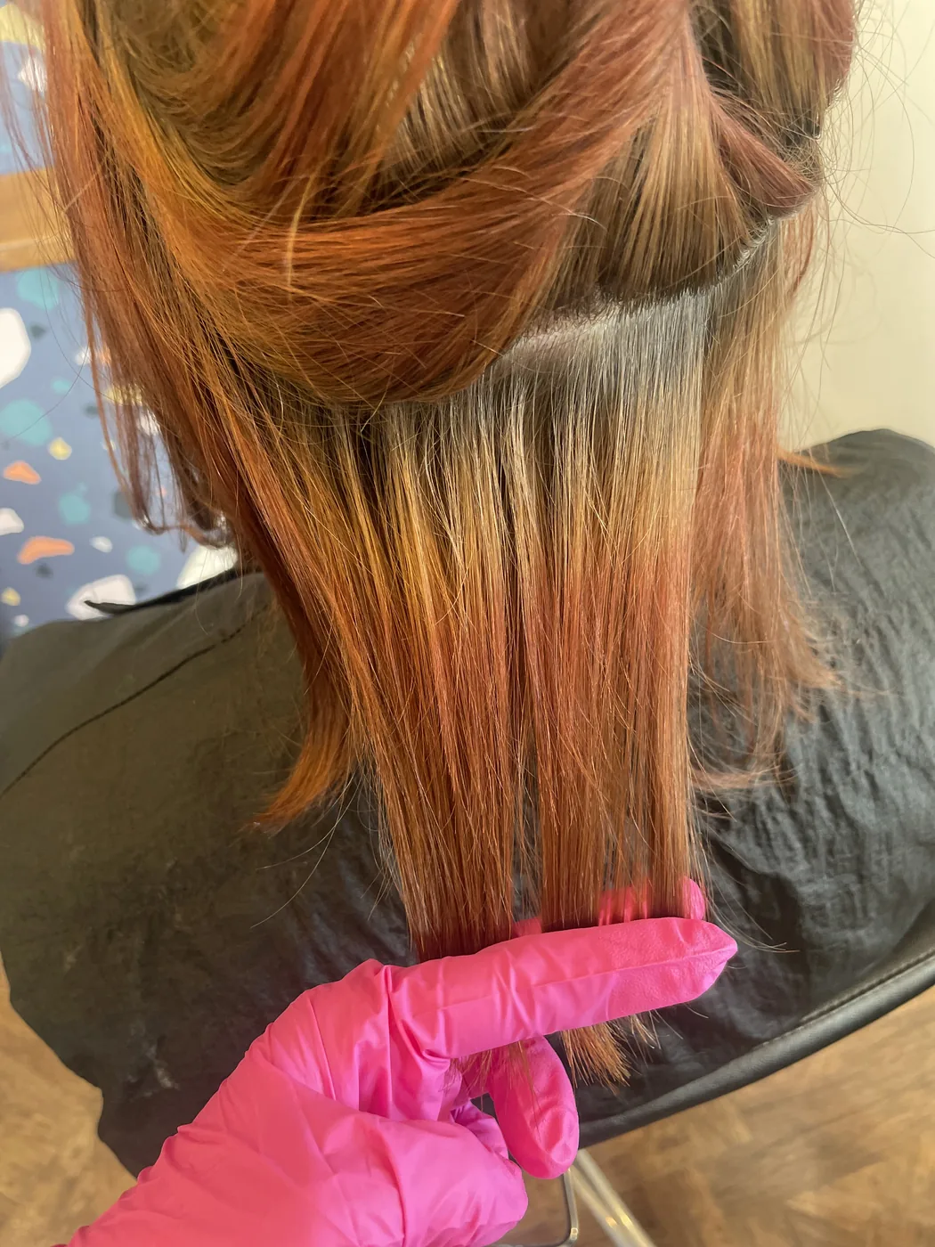 Close-up of uneven, banded hair color — faded natural root growing into vivid orange box-dye ends — before Anna's color correction.