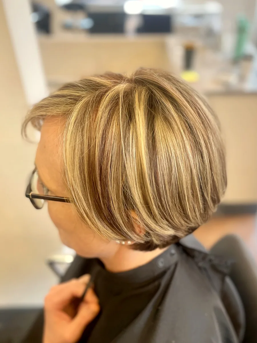 Chic short blonde cut with dimensional highlights, styled with soft volume — side profile.