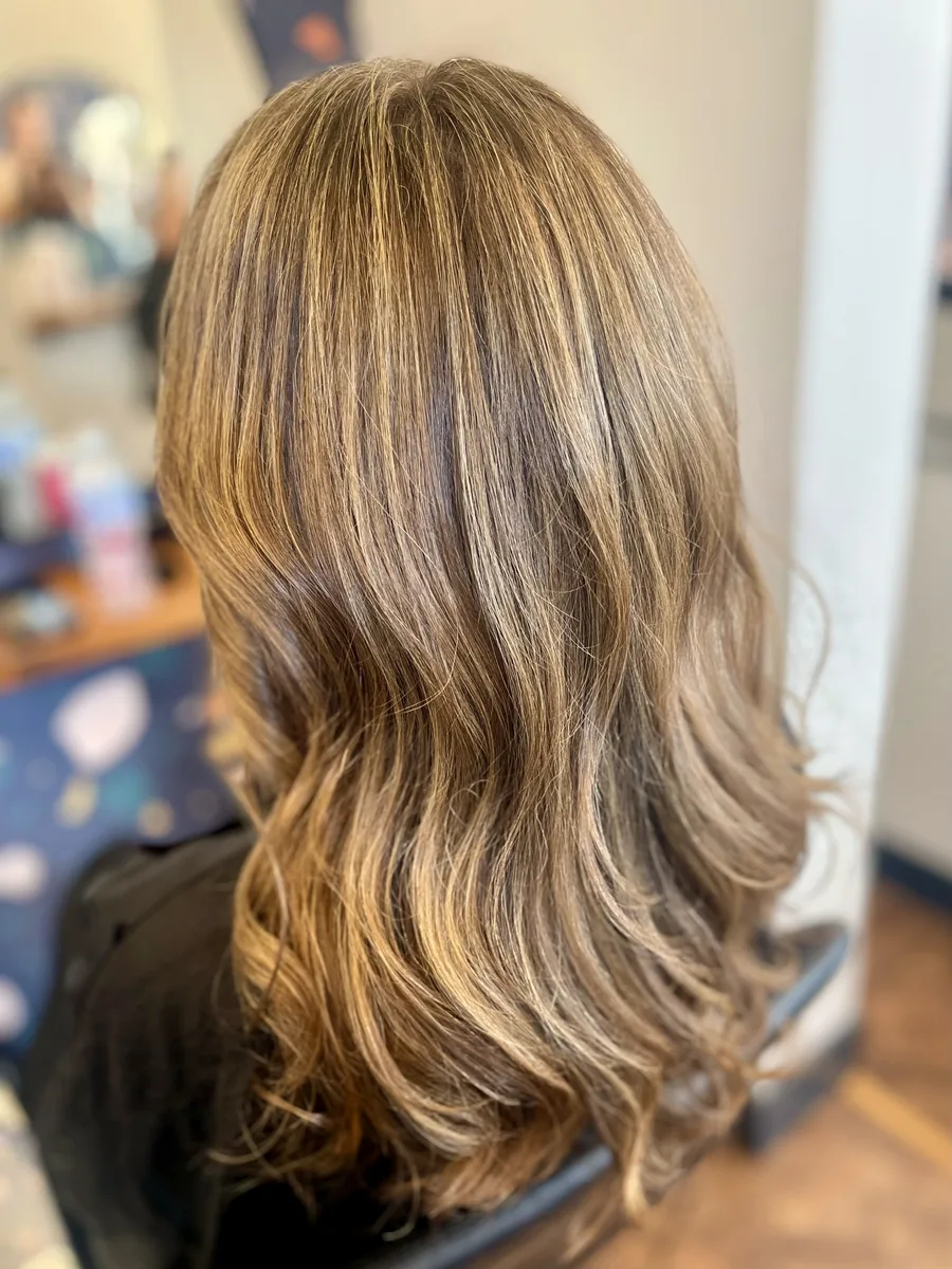 Caramel-bronde balayage waves on long layered hair — back view.