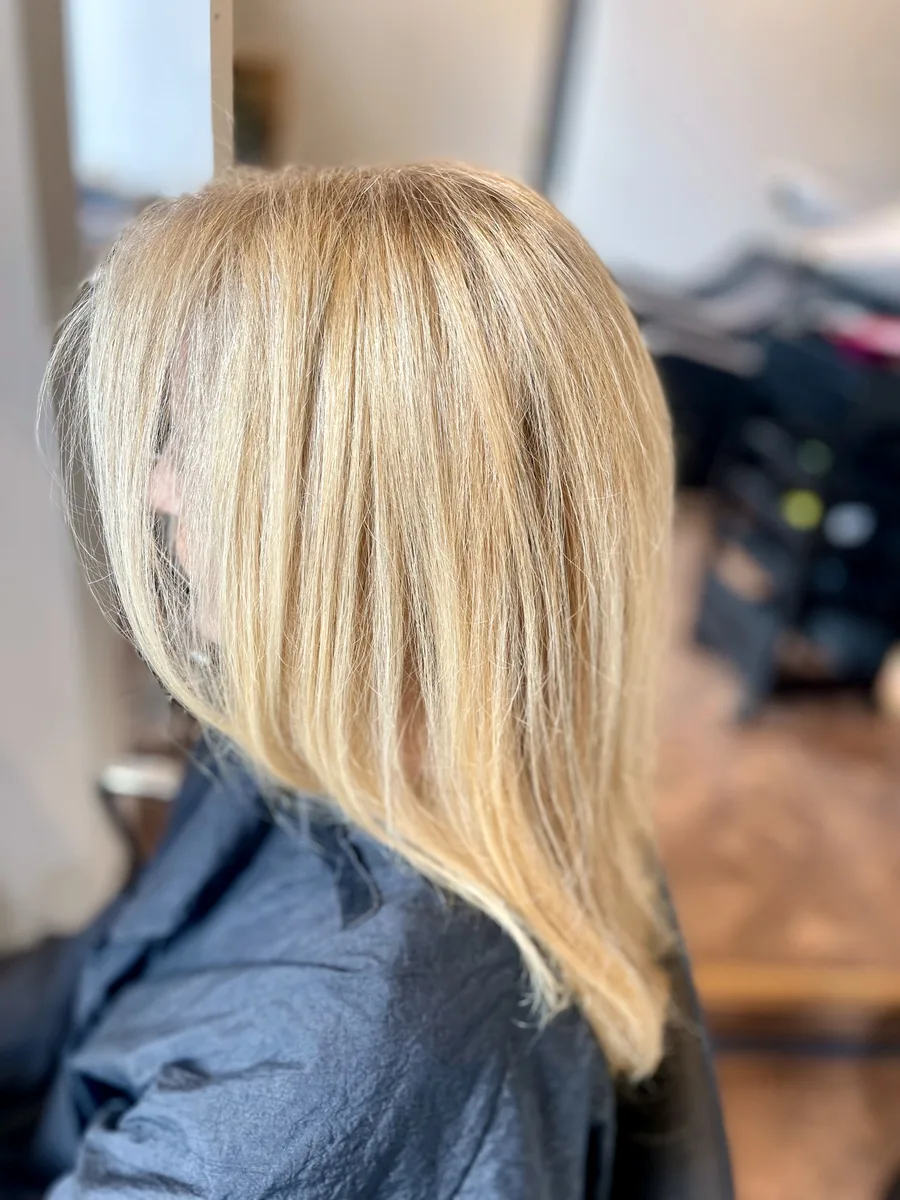 Bright blonde mid-length cut, styled straight and sleek — side view.
