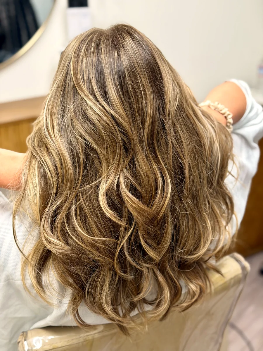 Bright, dimensional color blended through long layers, finished in soft waves — balayage by Anna Berglund.